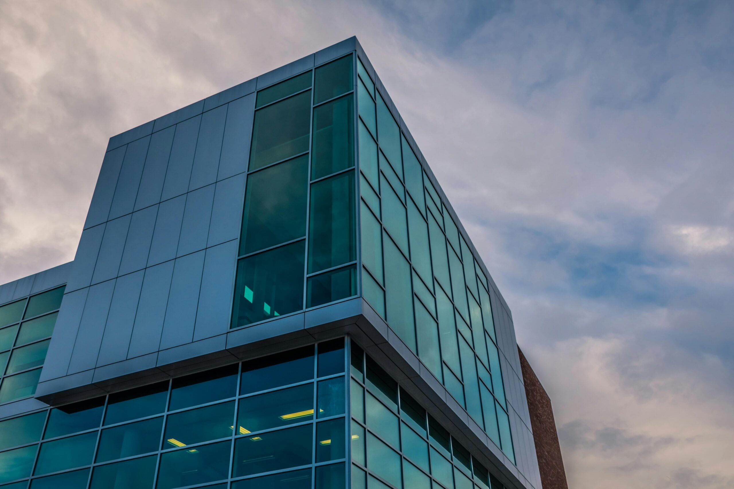 A contemporary building with glass facade under a cloudy sky, showcasing modern architecture.